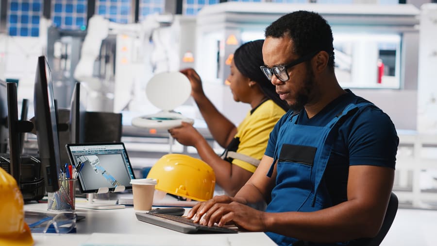 Technicien travaillant sur un poste informatique avec plan 3D